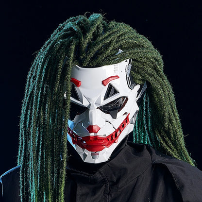 Person wearing a white mask with red accents and green dreadlocks against a black background